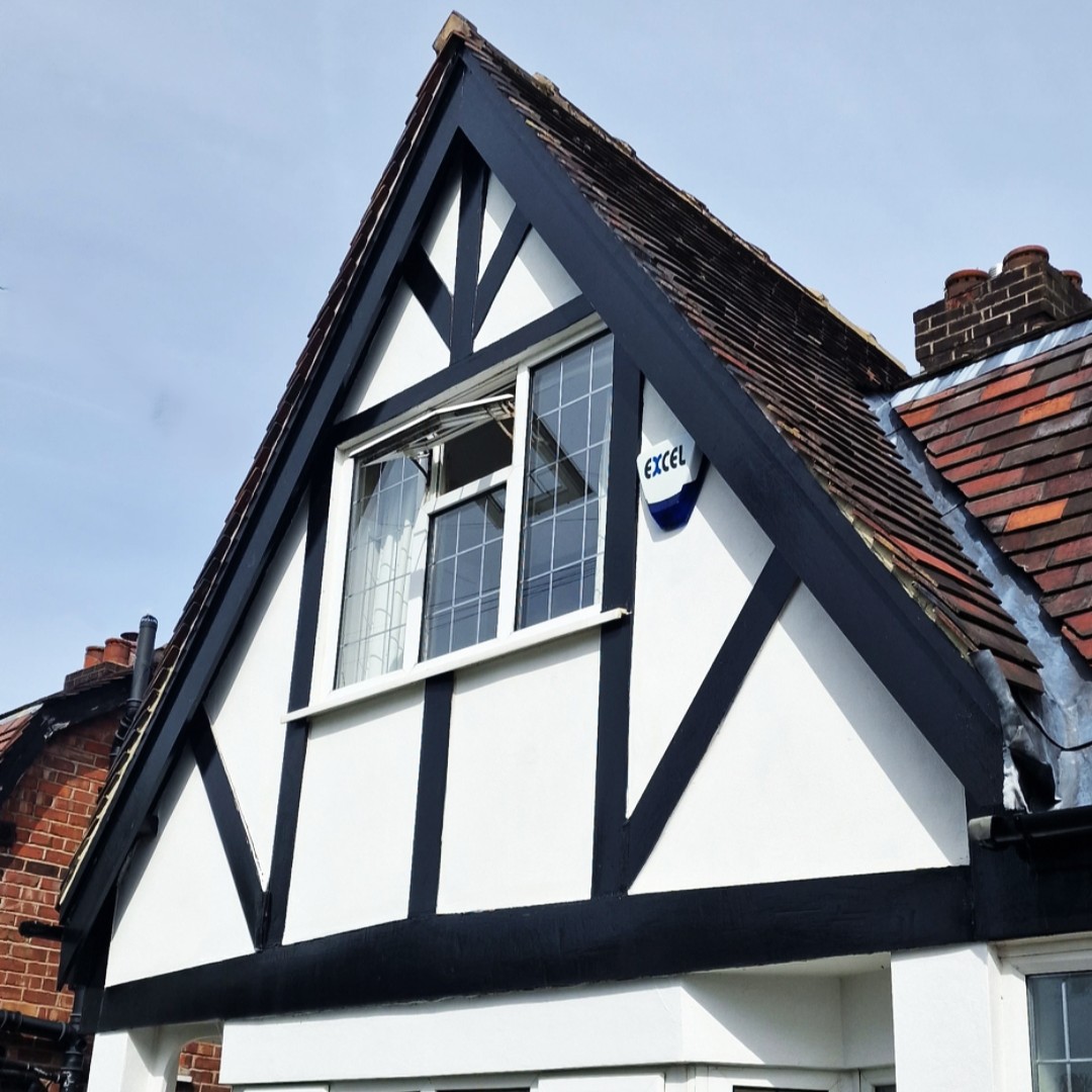Close-up of a house gable with smooth white K-rend render and black timber detailing under a tiled roof.